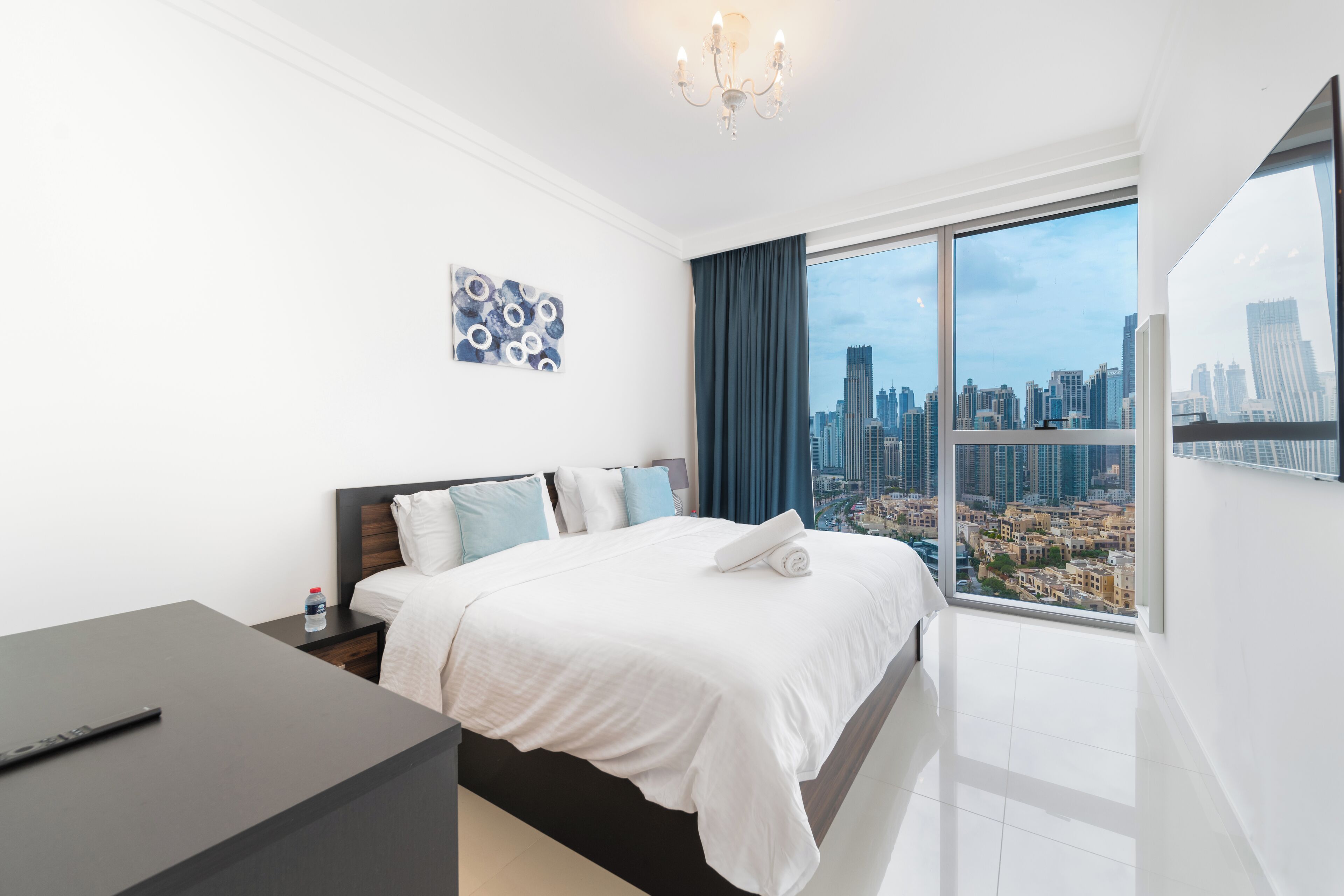 Une chambre d’hôtel moderne avec un grand lit, un bureau et une vue sur le panorama urbain.