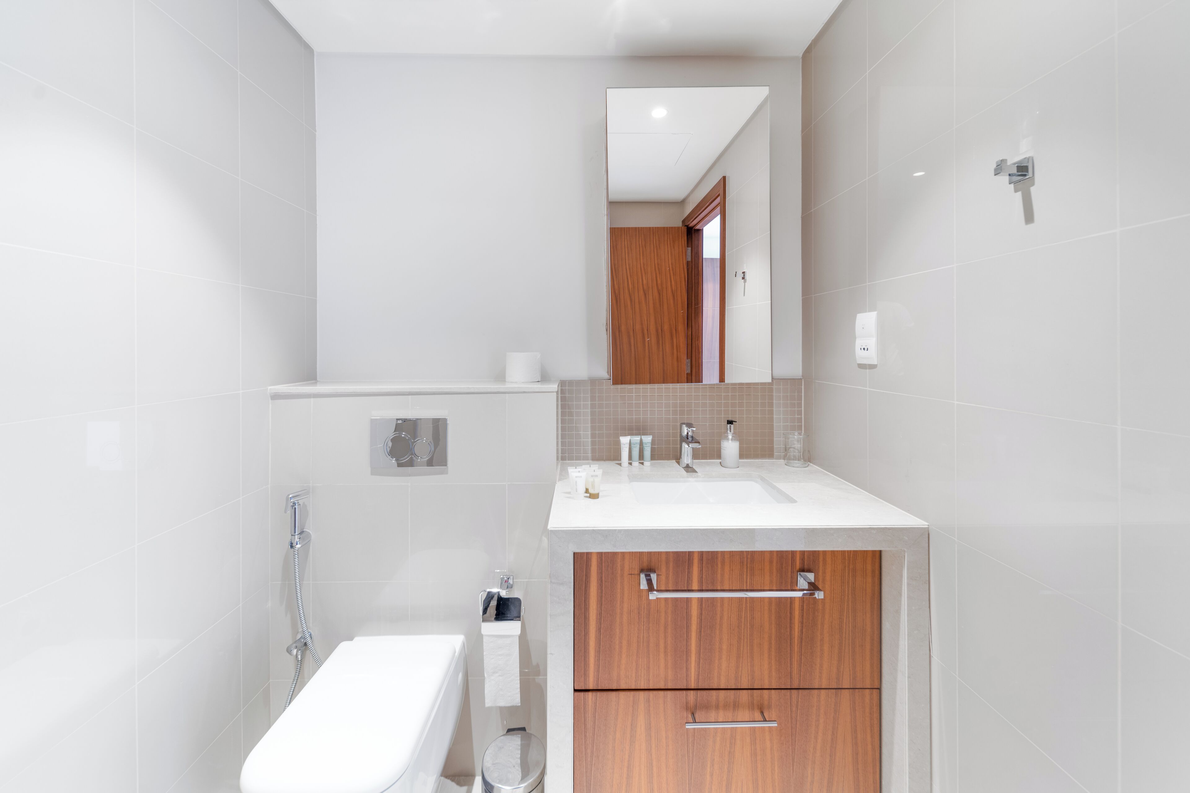 A modern bathroom with a white sink, wooden cabinets, and a mirror above the vanity.