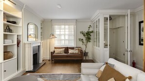 A living room with a fireplace, a sofa, a coffee table, and a bookshelf. - Charming Family Retreat – 4BR Marylebone (Greater London)