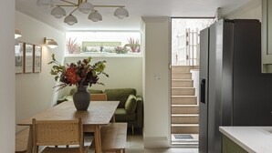 A modern kitchen with a dining area, a staircase leading to an upper level, and a view of the outside. - Charming Family Retreat – 4BR Marylebone (Greater London)