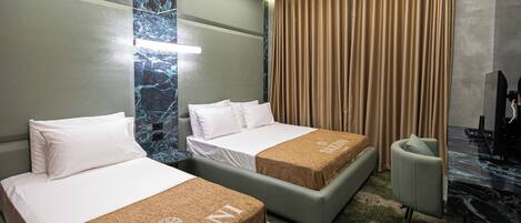 A hotel room with two beds, a desk, a chair, and a large window with curtains.