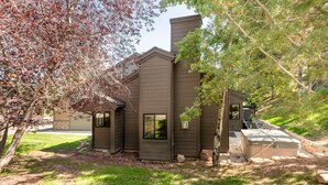 A two-story house with a brown exterior, a chimney, and a hot tub in the backyard. - Stylish 4BR Canyons Village-Walk to Cabriolet-Hidden Creek 37D (Park City)