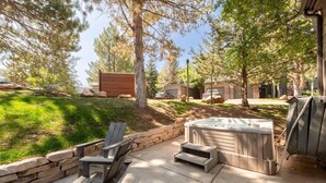 An outdoor patio area with Adirondack chairs, a hot tub, and a stone wall. - Stylish 4BR Canyons Village-Walk to Cabriolet-Hidden Creek 37D (Park City)