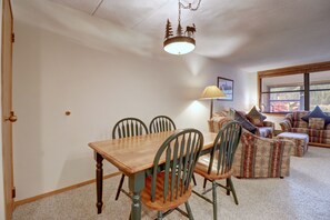 A dining area with a wooden table and chairs, a hanging light fixture, and a window with a view of the outdoors. - Vs453 Village Square 1 Br 1 Ba 1 Bedroom Condo (Copper Mountain)