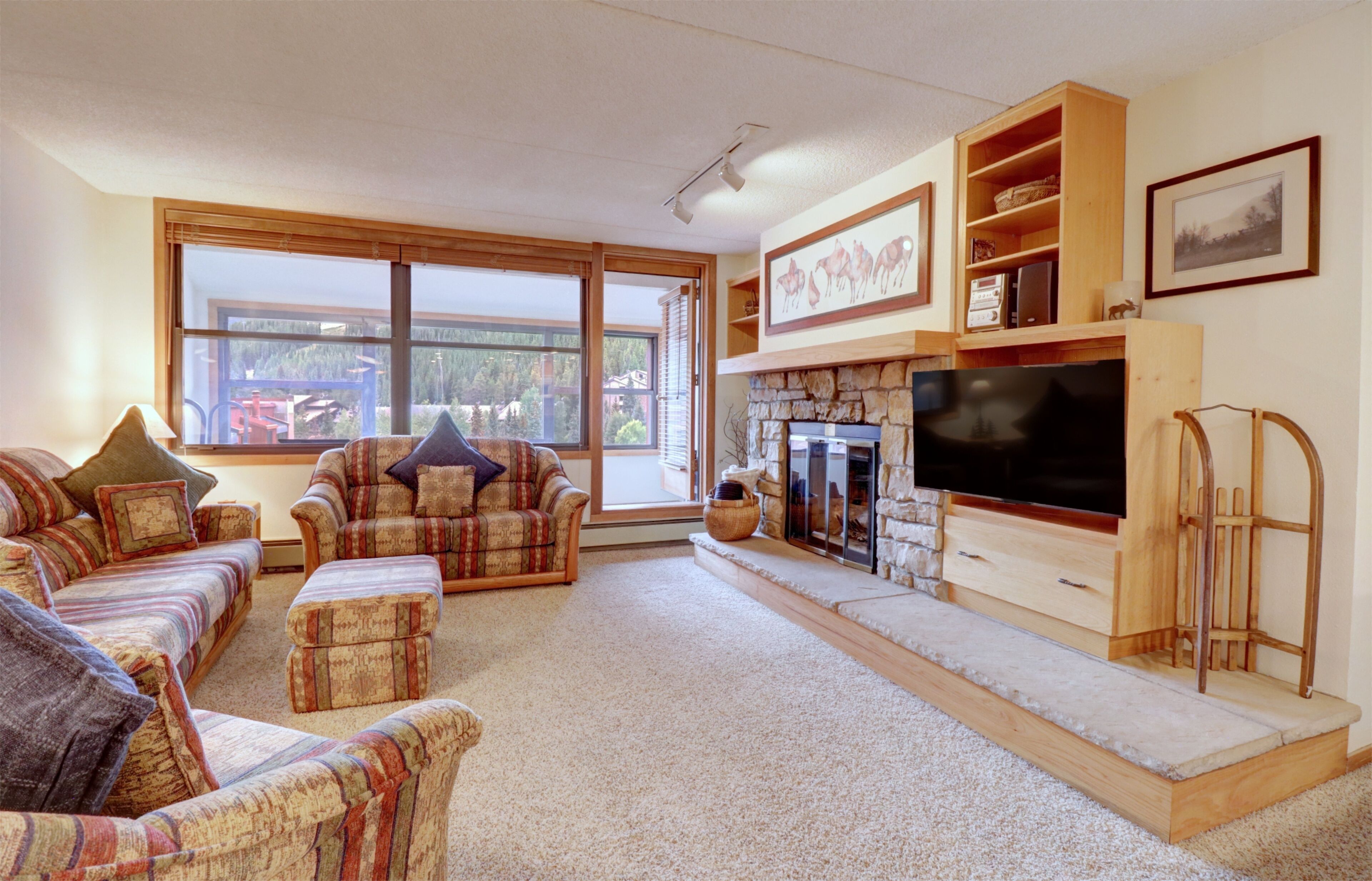 A cozy living room with a fireplace, a large window, and a television.