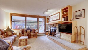 A cozy living room with a fireplace, a large window, and a television.