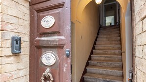 Eine Holztür mit zwei Schildern, einer Treppe und einer Ziegelwand.
