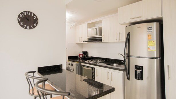 A modern kitchen with a stainless steel refrigerator, a microwave, and a coffee maker on the counter. - Apartamentos Oslo-by Medellin Experience (Medellin)