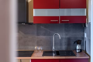 A modern kitchen with a black induction cooktop, a stainless steel faucet, and a coffee maker.