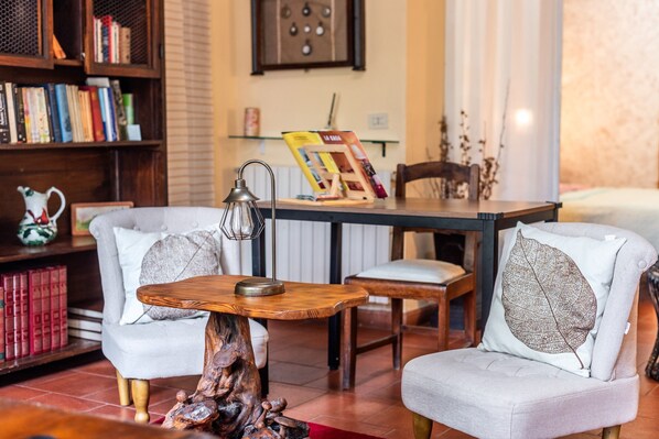 A cozy living room with two armchairs, a wooden coffee table, a bookshelf, and a painting on the wall.