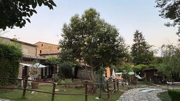 Un patio con senderos de piedra, cercas de madera rústica y edificios tradicionales.