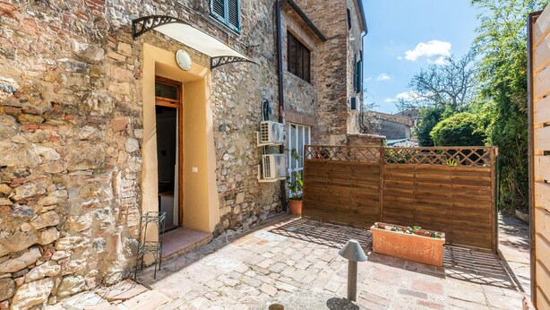 Un edificio in pietra con una porta di legno, una piccola area relax esterna e un recinto di legno.