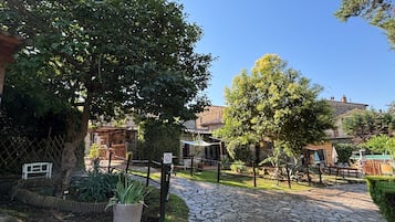 A stone pathway leading to a rustic building with a wooden fence and greenery.