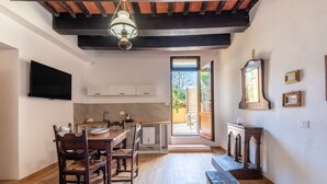 Una stanza con pavimento in legno, un tavolo da pranzo con sedie, una TV montata a parete, uno specchio grande e una finestra vista esterna.