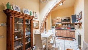 A kitchen with a dining area, wooden cabinets, a microwave, and a tiled floor. - Apartment 'Glicine - Antiche Dimore' with Shared Pool, Wi-Fi, and Air Conditioning (Siena)