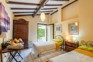 Un dormitorio con cama, escritorio, armario y puerta que da a un balcón.