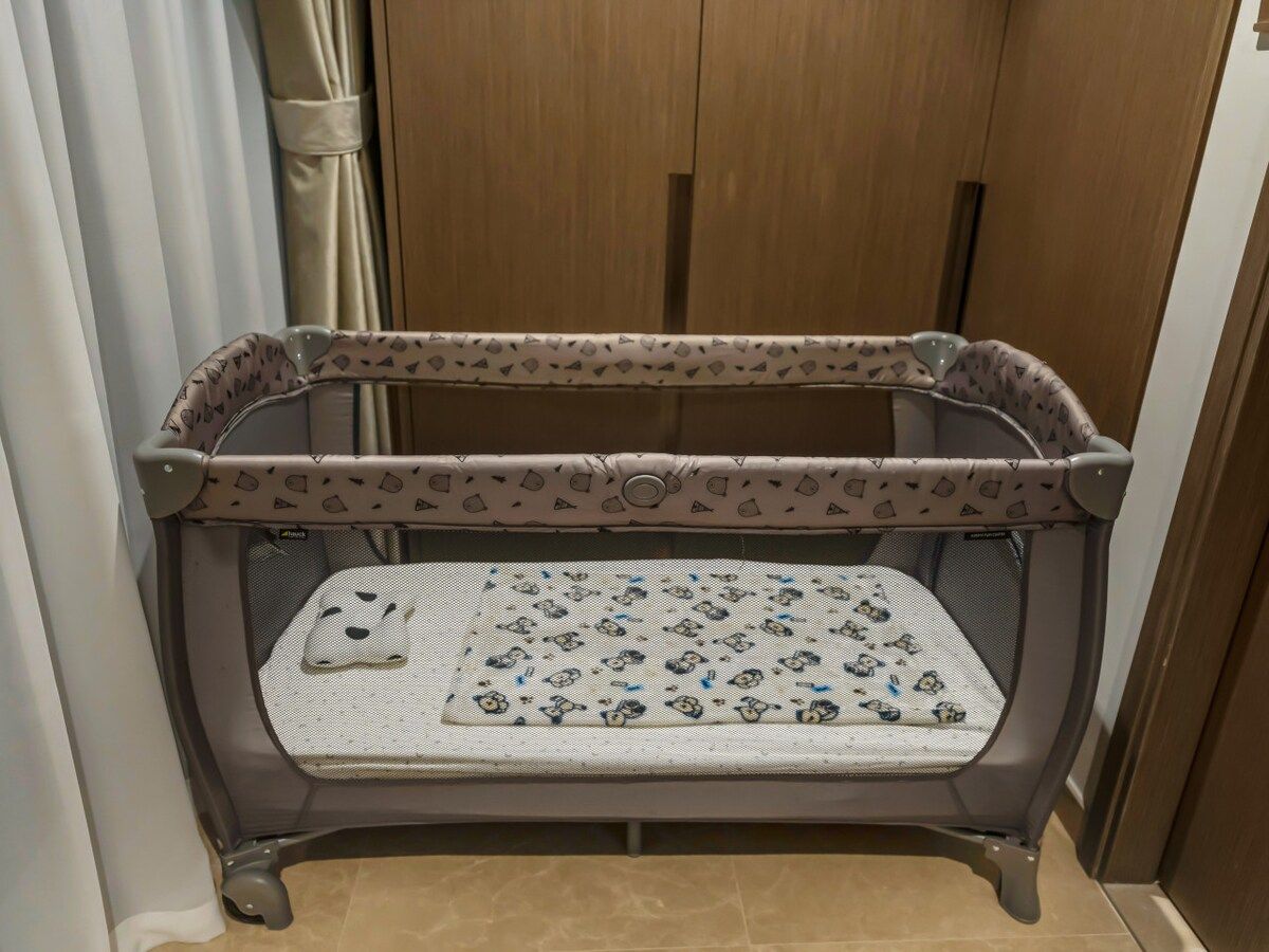 A baby crib with a patterned mattress and a safety rail.