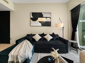 A modern living room with a dark sofa, a lamp, and a painting on the wall.