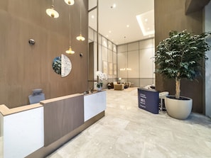 A modern reception area with a reception desk, seating area, and a large potted plant. - New 1BR | Burj Khalifa Infinity Pool | Dubai Mall (Dubai)