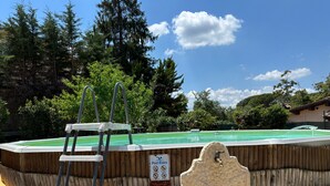 Une piscine dotée d’une terrasse en bois, d’une fontaine en pierre et d’un escalier menant à l’intérieur de la piscine.