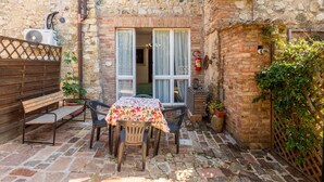 Un bâtiment en pierre doté d’une cour, d’une table avec des chaises, d’un banc et d’un extincteur.