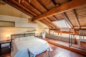Ein Schlafzimmer mit Holzboden, einem Bett, einem Nachttisch, einer Bank und einem kleinen Tisch mit Stühlen.