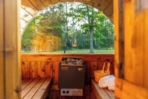 Eine Holzsauna mit einer Bank, einem Steinkamin und einem Holzeimer.