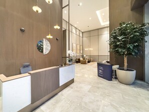 A reception area with a reception desk, a potted plant, and a seating area with sofas.