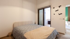Ein Schlafzimmer mit einem Bett, einer Wand mit einem Motivationsspruch, einer Schiebetür und Blick ins Freie.