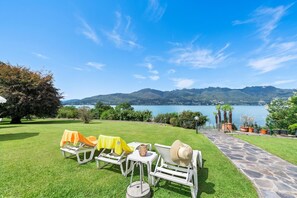 Un giardino con posti a sedere all'aperto e vista su un lago e montagne.