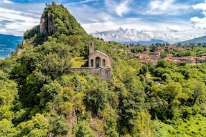 A small stone church on a hill with a village in the background.