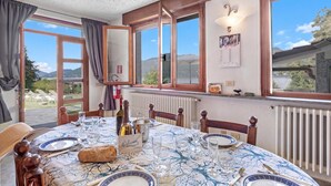 Un comedor con una mesa preparada para dos personas, una botella de vino y vistas al exterior.