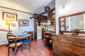 Un coin repas avec une table et des chaises en bois, une horloge et un miroir au mur.