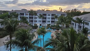 Ein Resort mit mehrstöckigen Gebäuden, einem Schwimmbecken und Palmen.