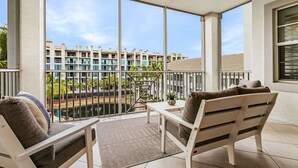 Ein Balkon mit einer weißen Couch, einem kleinen Tisch und einem Deckenventilator.