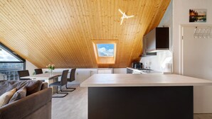 Una cucina moderna con soffitto in legno, un lucernario e un'area pranzo con un divano.