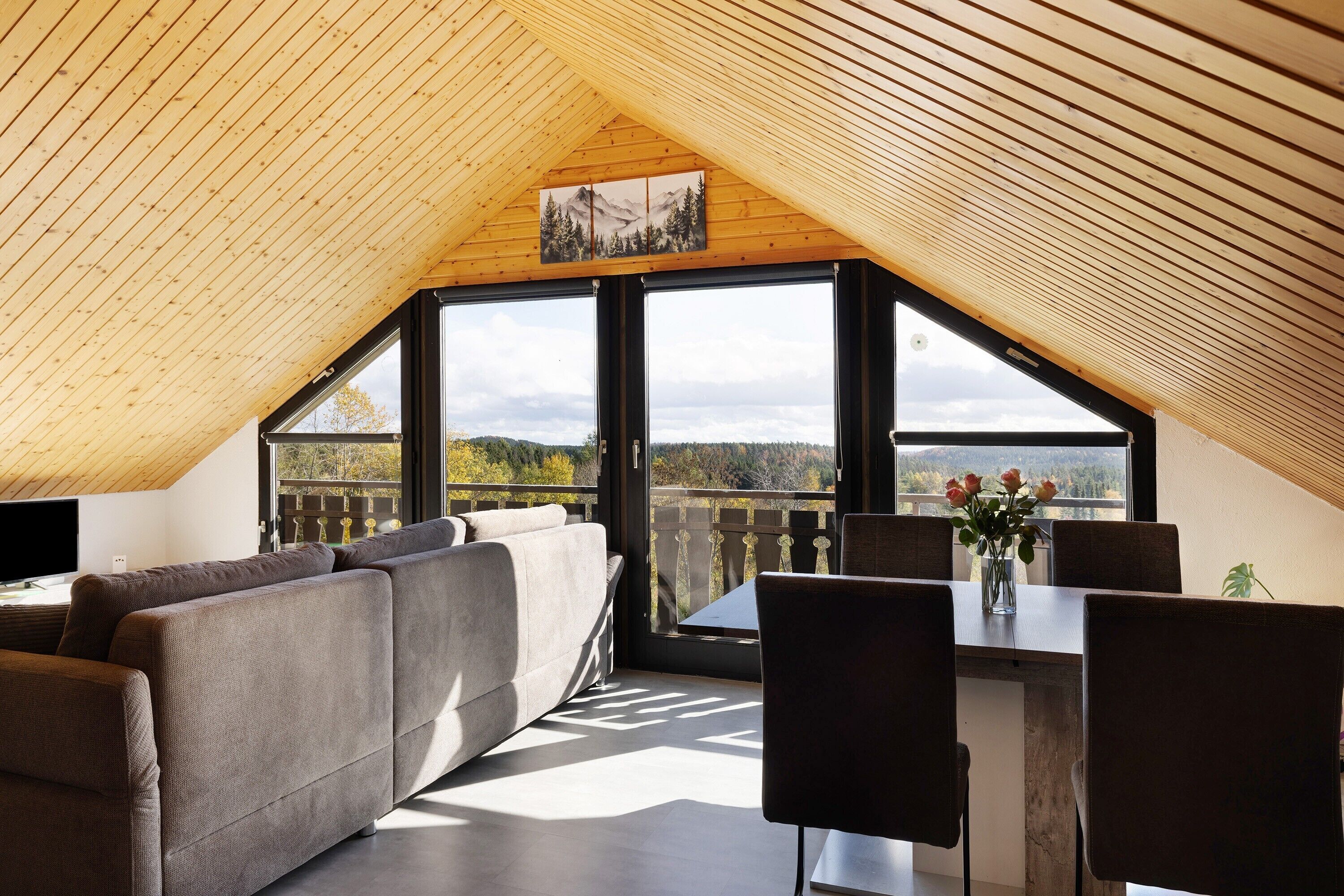 Une chambre de style loft moderne, avec un plafond en pente, de grandes fenêtres, un canapé, une table à manger et des chaises.