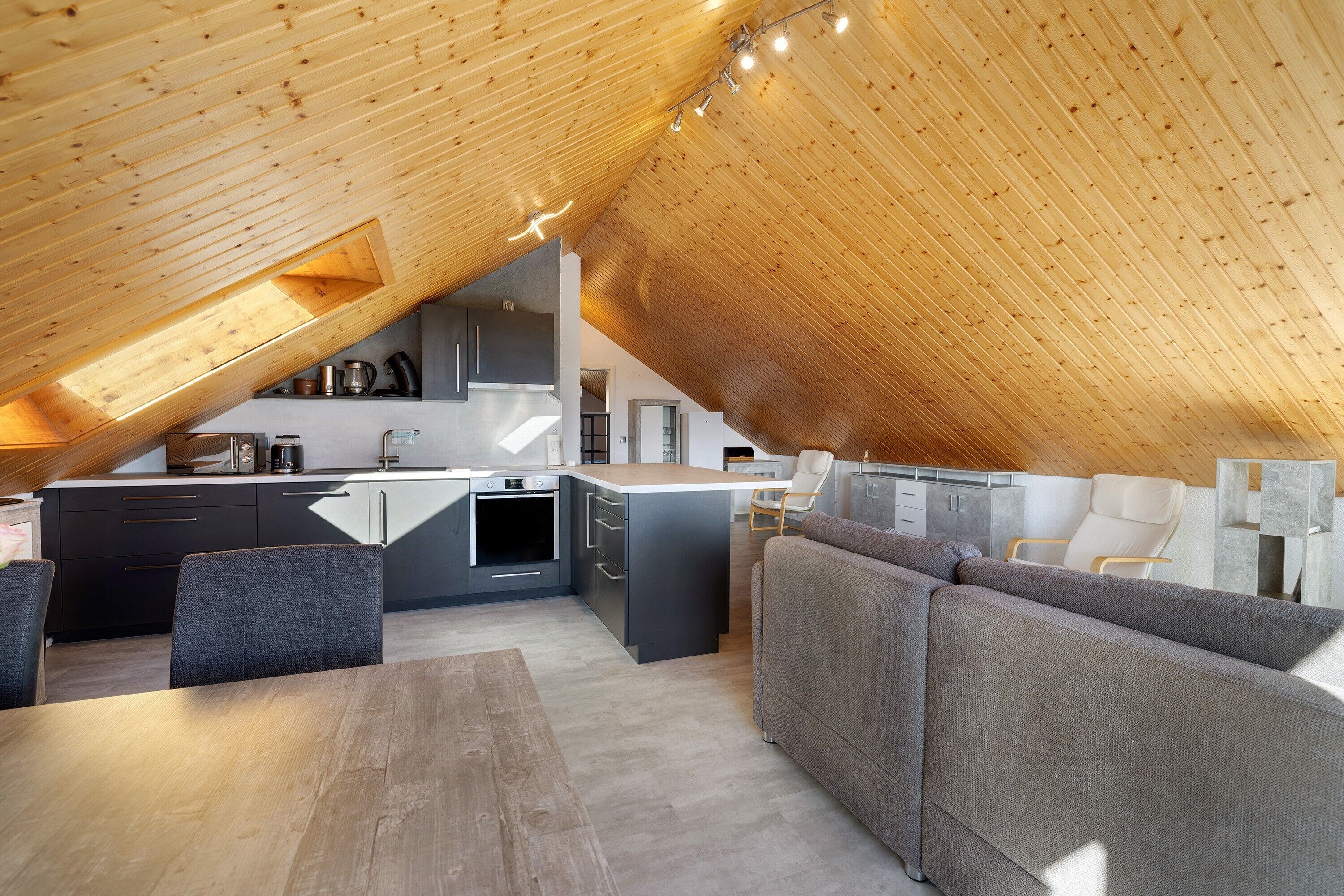 Een zolderappartement met een keuken, eethoek en zithoek.