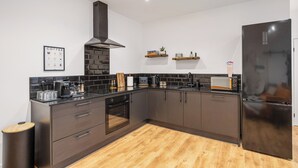 A modern kitchen with dark cabinetry, a stainless steel refrigerator, and a black range hood. - ELEVATED ESCAPE - 3 bedroom house with rooftop terrace,sauna,hot tub&cinema room (Hythe)