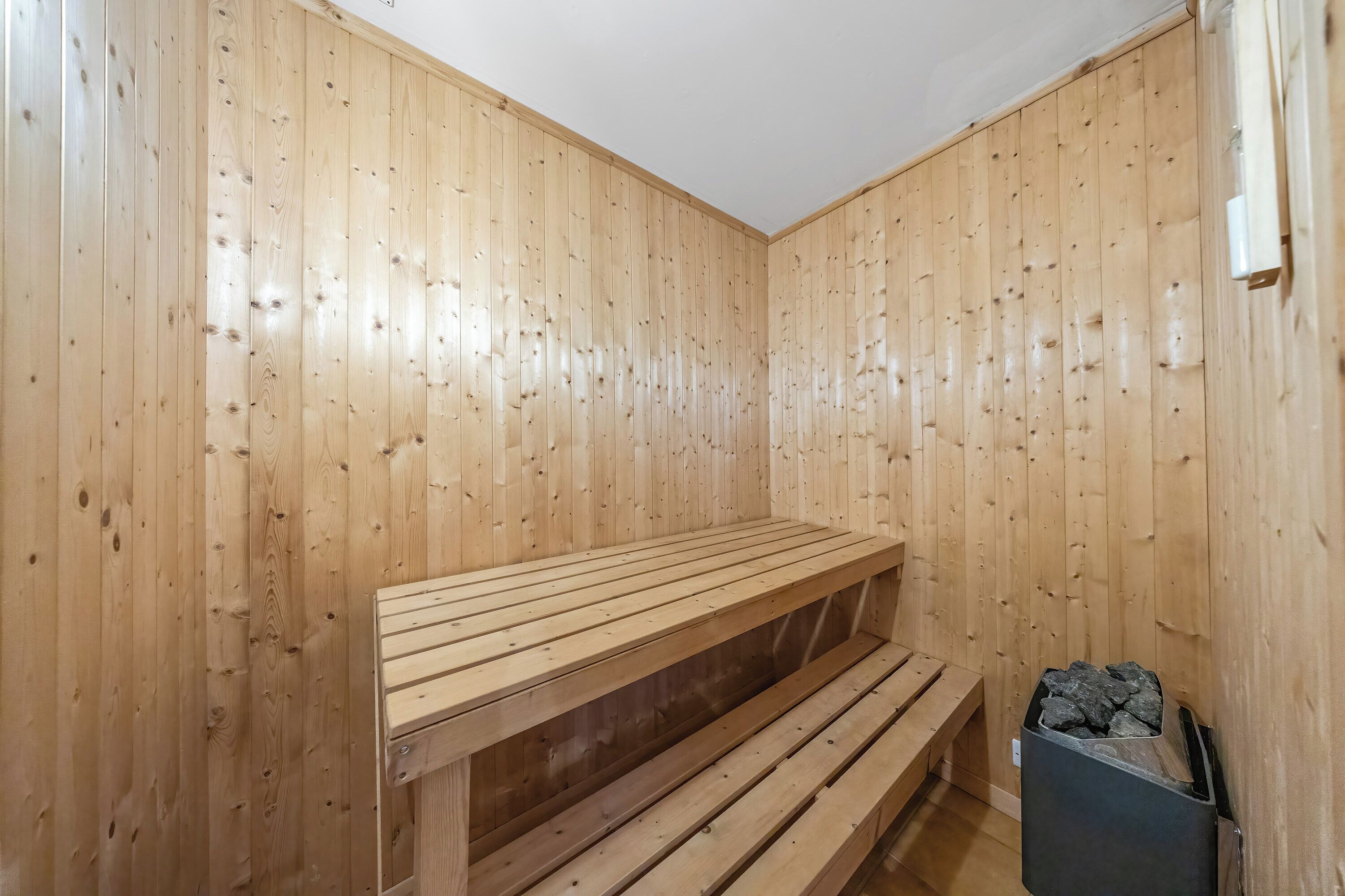 Un sauna avec des murs et des bancs en bois.