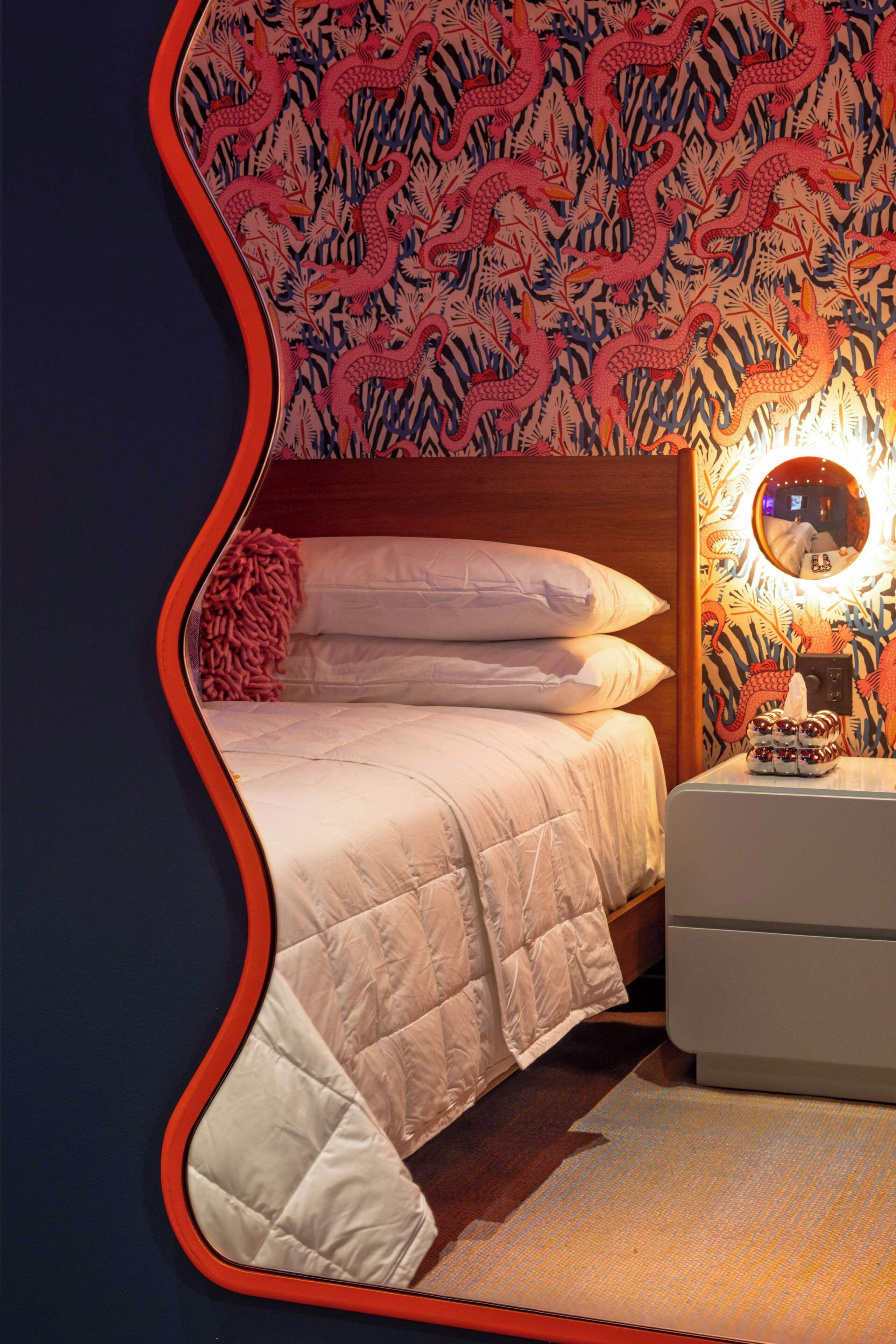 A bed with a quilted blanket, a bedside table with a decorative item, and a wall with a dragon pattern.