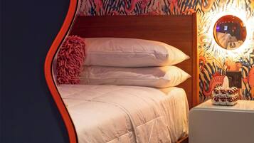 A bed with a quilted blanket, a bedside table with a decorative item, and a wall with a dragon pattern.