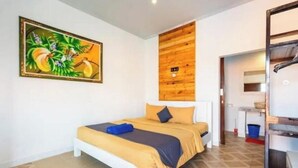 Une chambre à coucher avec un lit, un mur décoratif en bois, un tableau, et une salle de bain visible à travers une porte ouverte.