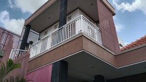 Un bâtiment moderne doté d’un balcon, d’une clôture rose et surplombant un ciel dégagé.