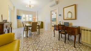 A dining area with a table and chairs, a sofa, and a desk with a computer. - Estate4home - Casa Anna 1944 (Sorrento)
