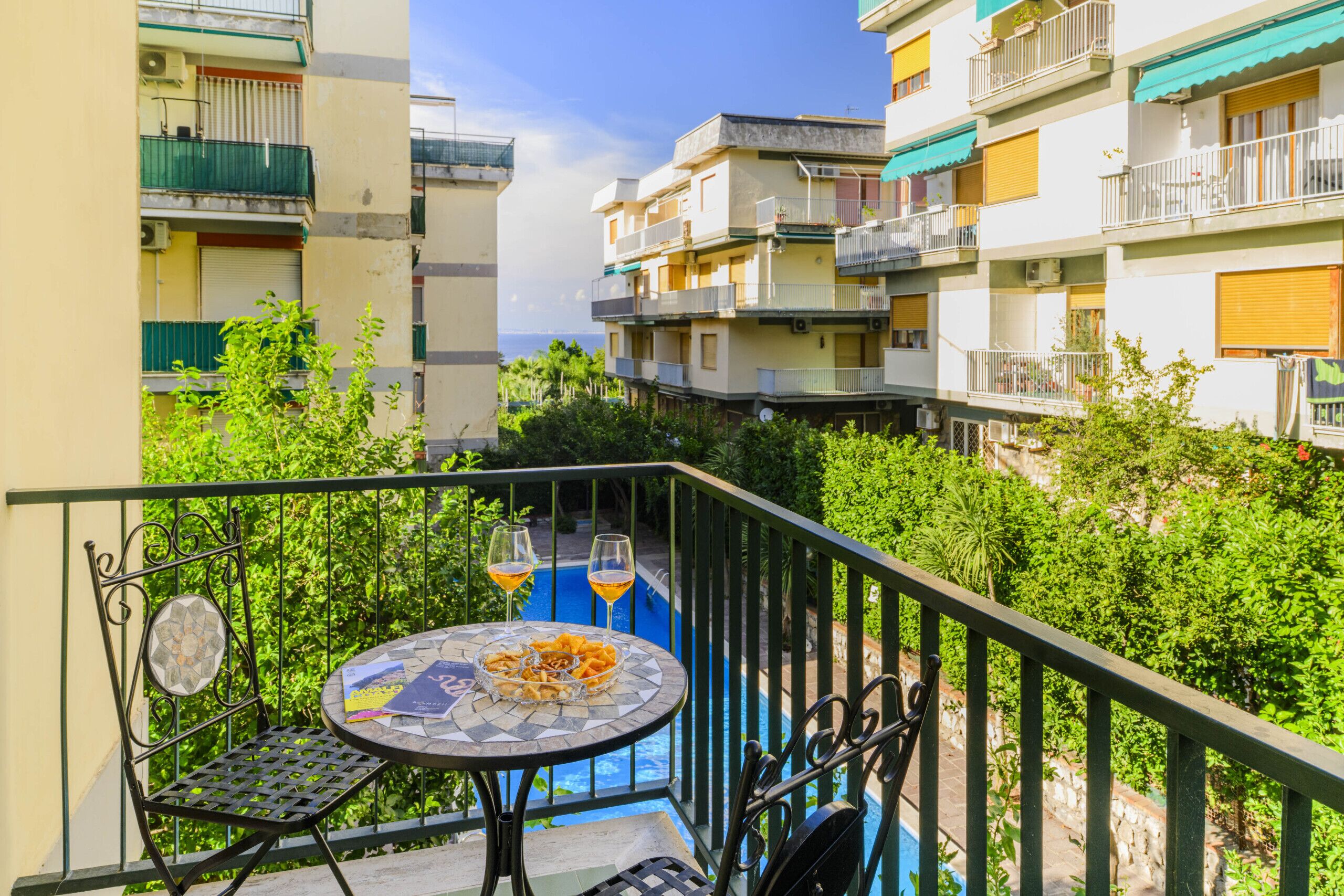 Ein Balkon mit einem runden Tisch, zwei Stühlen und zwei Gläsern Orangensaft.