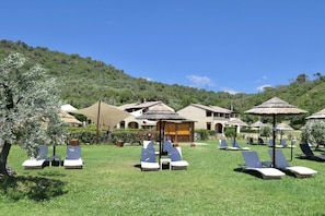 A resort with outdoor lounge chairs and umbrellas, surrounded by greenery and buildings. - Spacious three-room apartments (about 50 square meters), they are arranged as follows: <br>living room with kitchenette and double sofa bed, double bedroom, bedroom with one or two single beds and bathroom with shower.Equipped with a large covered balcon (Campiglia Marittima)