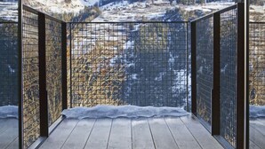 A balcony with a metal railing, a wooden floor, and a view of snow-covered mountains. - Mineral Lodge - Les Arcs Paradiski (villaroger)