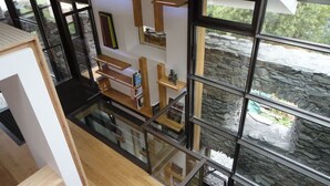 A modern interior with a glass staircase, wooden shelves, and a stone wall view. - Mineral Lodge - Les Arcs Paradiski (villaroger)