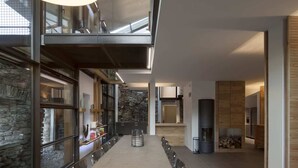 A modern dining area with a long table, stone walls, and a fireplace. - Mineral Lodge - Les Arcs Paradiski (villaroger)